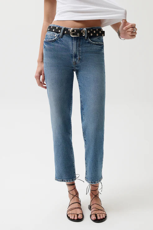 Person wearing light blue jeans with a polka dot belt on a white background