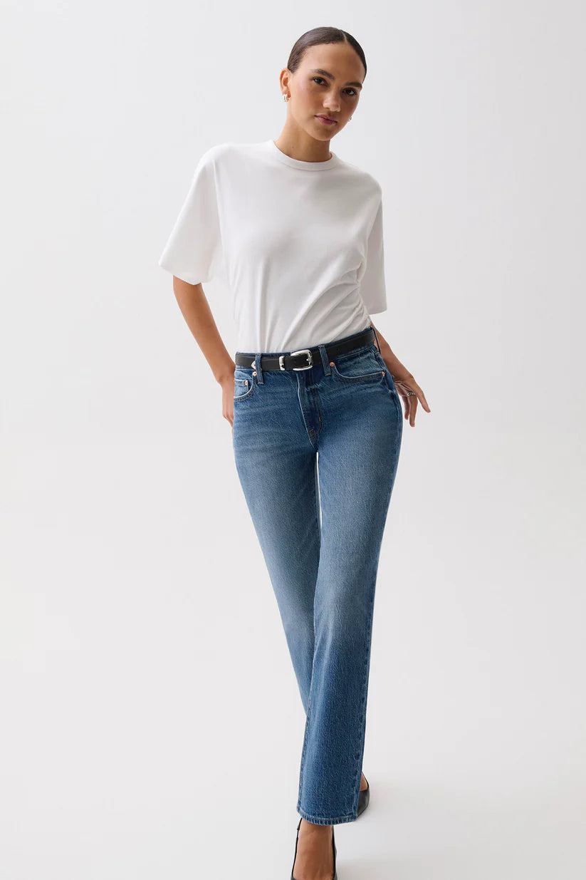 Woman wearing a white t-shirt and blue jeans on a plain background