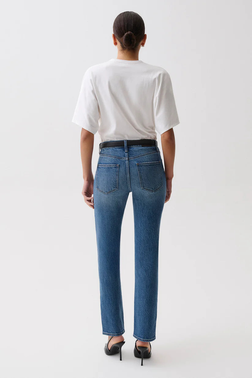 Person wearing a white t-shirt and blue jeans on a plain background