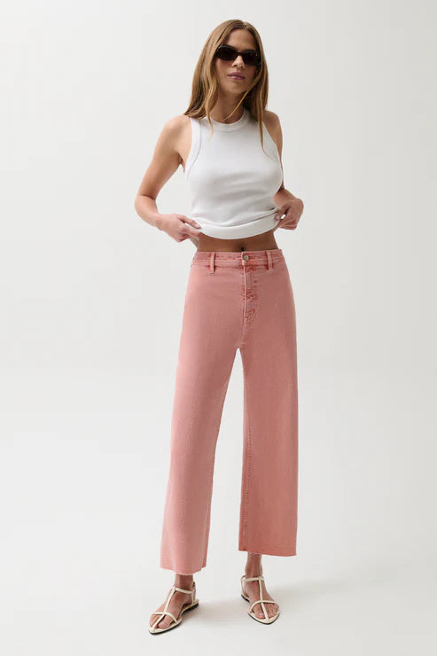 Woman wearing a white tank top and pink pants on a white background