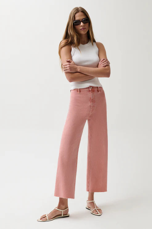 Woman wearing a white sleeveless top and pink pants on a white background