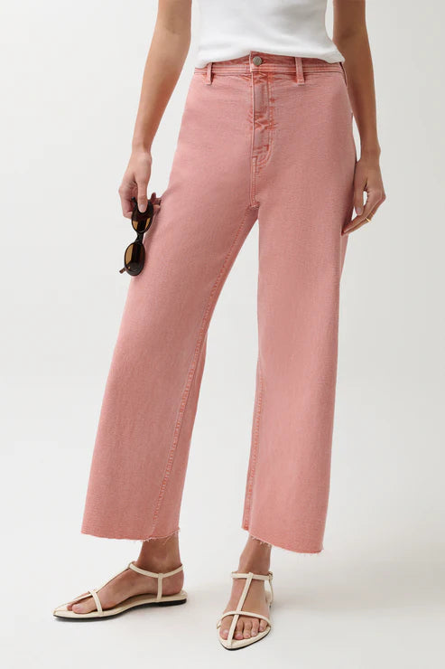 Person wearing pink jeans and a white top on a plain background