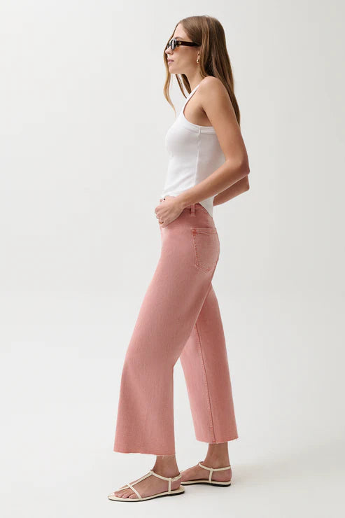 Woman wearing a white tank top and pink pants on a white background
