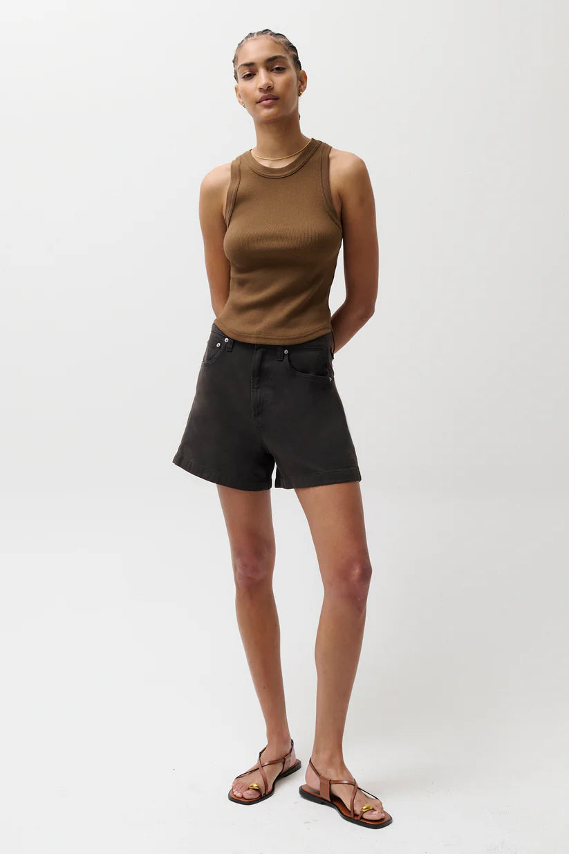 Person wearing a brown sleeveless top and black shorts on a white background