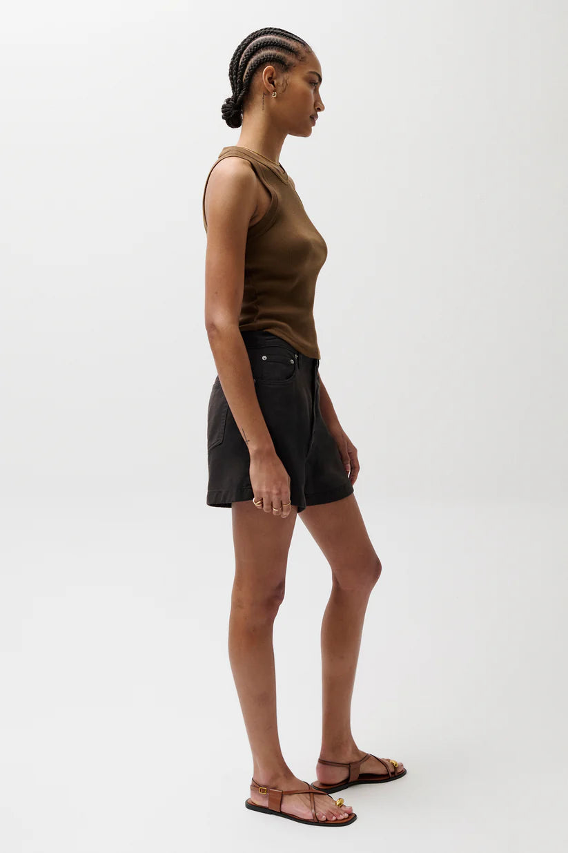 Woman wearing a brown tank top and black shorts on a white background