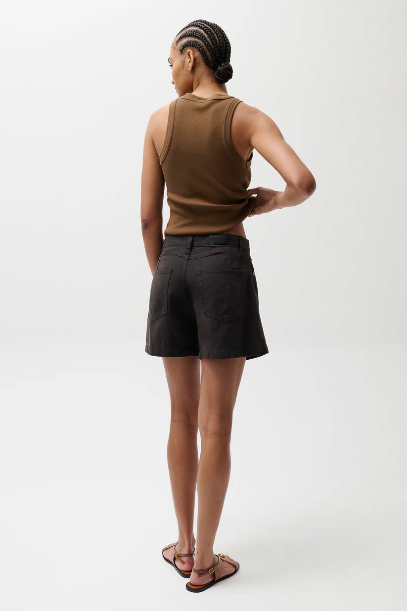 Person wearing a brown sleeveless top and black shorts on a white background