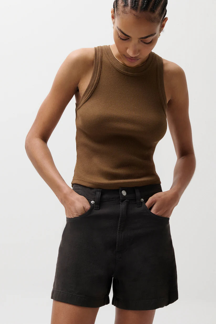 Woman wearing a brown tank top and black shorts on a plain background