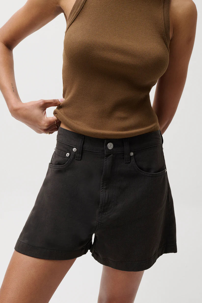 Person wearing a brown tank top and black shorts on a plain background