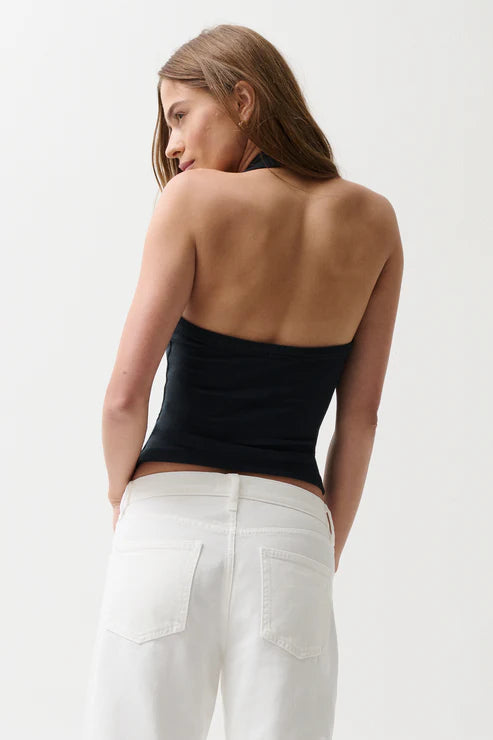 Woman wearing a black strapless top and white pants on a light gray background