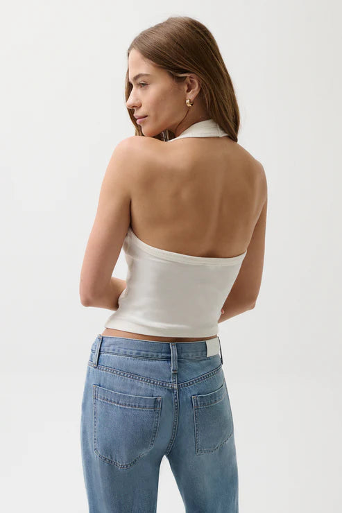Woman wearing a white strapless top and blue jeans on a plain background