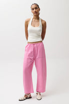 Woman wearing a white top and pink pants on a white background