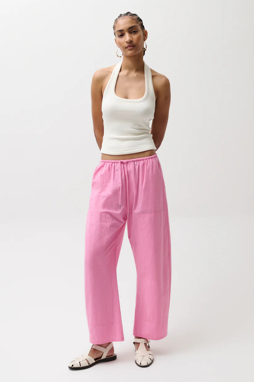 Woman wearing a white top and pink pants on a white background