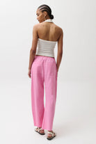 Woman wearing a white strapless top and pink pants on a white background