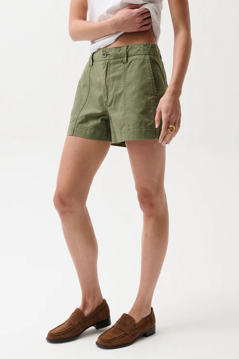 Person wearing green shorts and brown loafers on a white background
