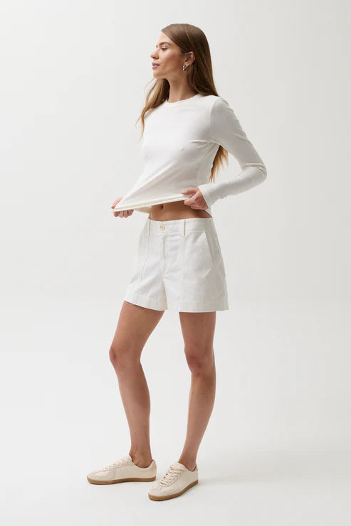 Woman wearing a white long-sleeve top and shorts on a white background