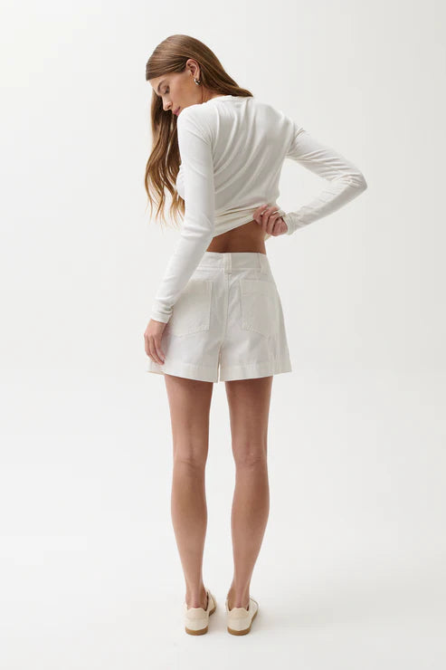 Woman wearing a white long-sleeve top and shorts on a white background