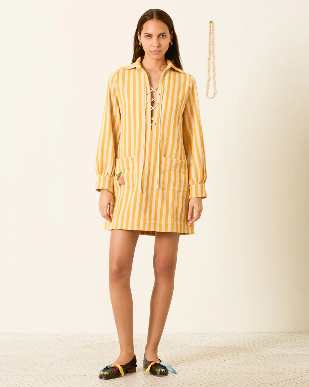 Woman wearing a yellow striped dress on a plain background