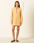 Woman wearing a yellow striped dress on a plain background