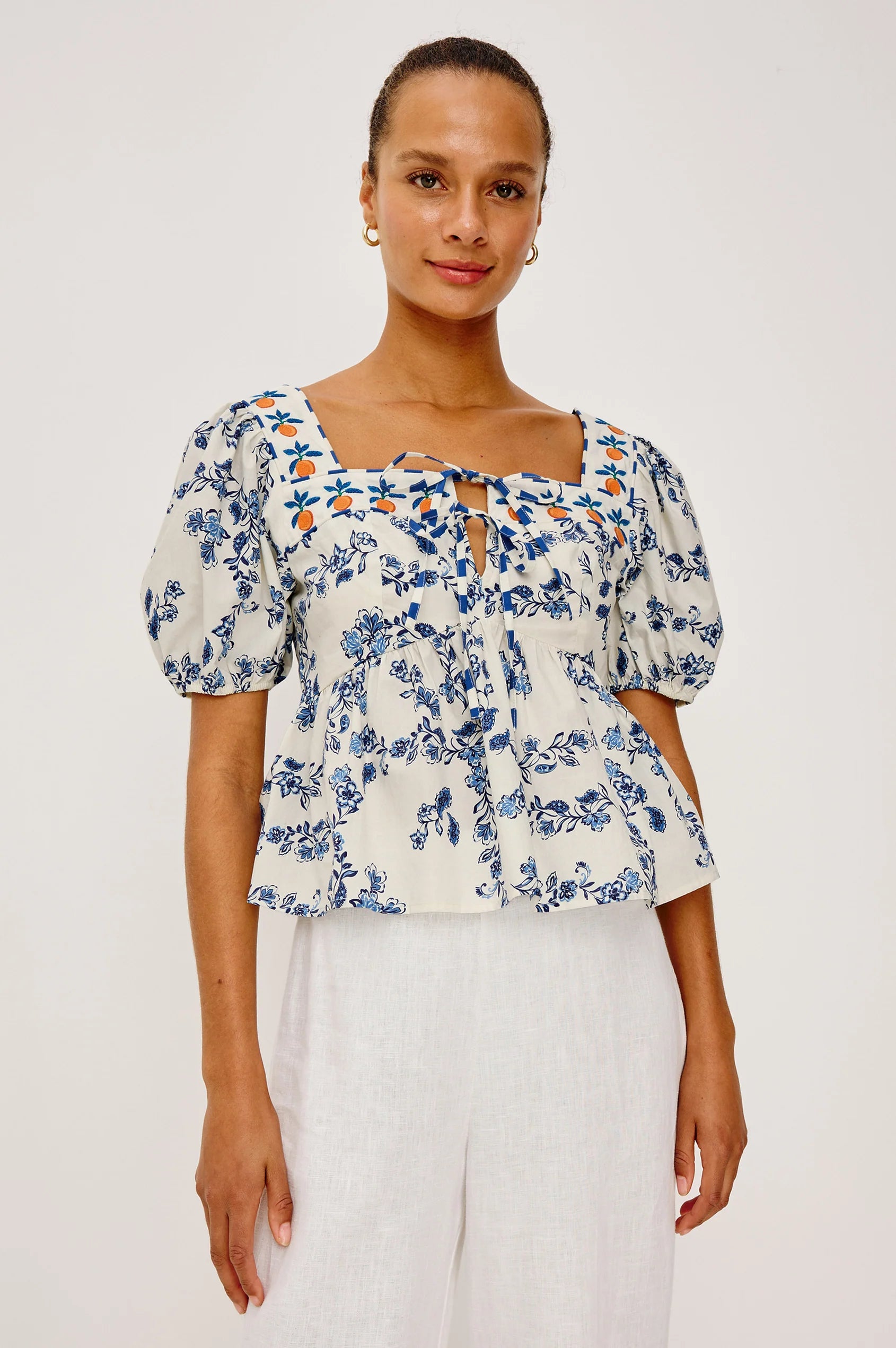 Woman wearing a floral blouse with puff sleeves on a white background