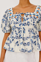 Floral blouse with blue and orange patterns on a plain background