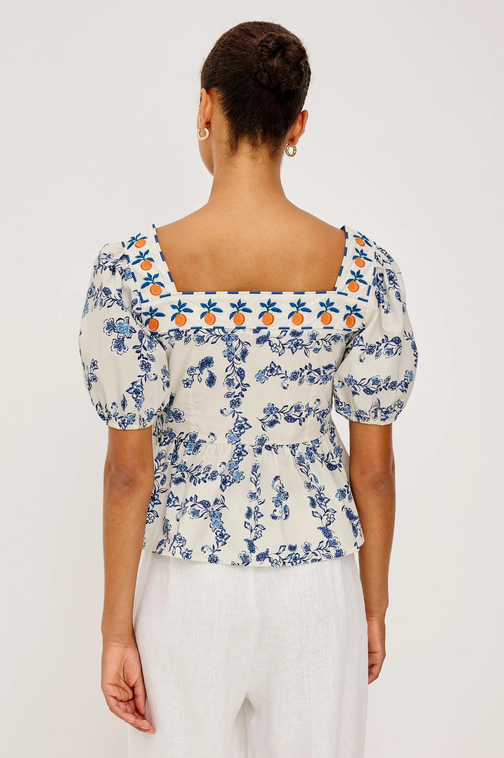 Woman wearing a floral blouse with puff sleeves on a plain background