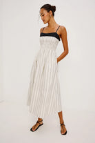 Woman wearing a white pleated dress with a black top on a white background