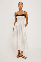 Woman wearing a white pleated dress with a black top on a white background