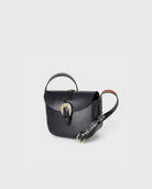 Black leather handbag with a strap on a light gray background