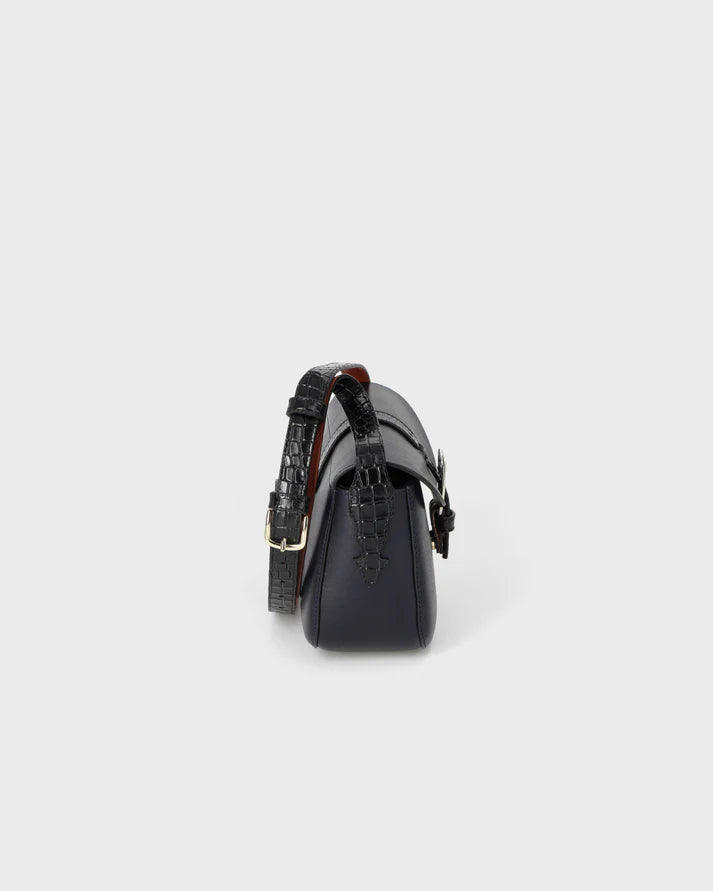 Black handbag with a textured strap on a light gray background