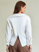 Woman wearing a white button-up shirt against a plain background