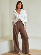 Woman wearing a white blouse and brown cargo pants against a neutral background