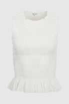 White sleeveless top with ruffled hem on a light gray background