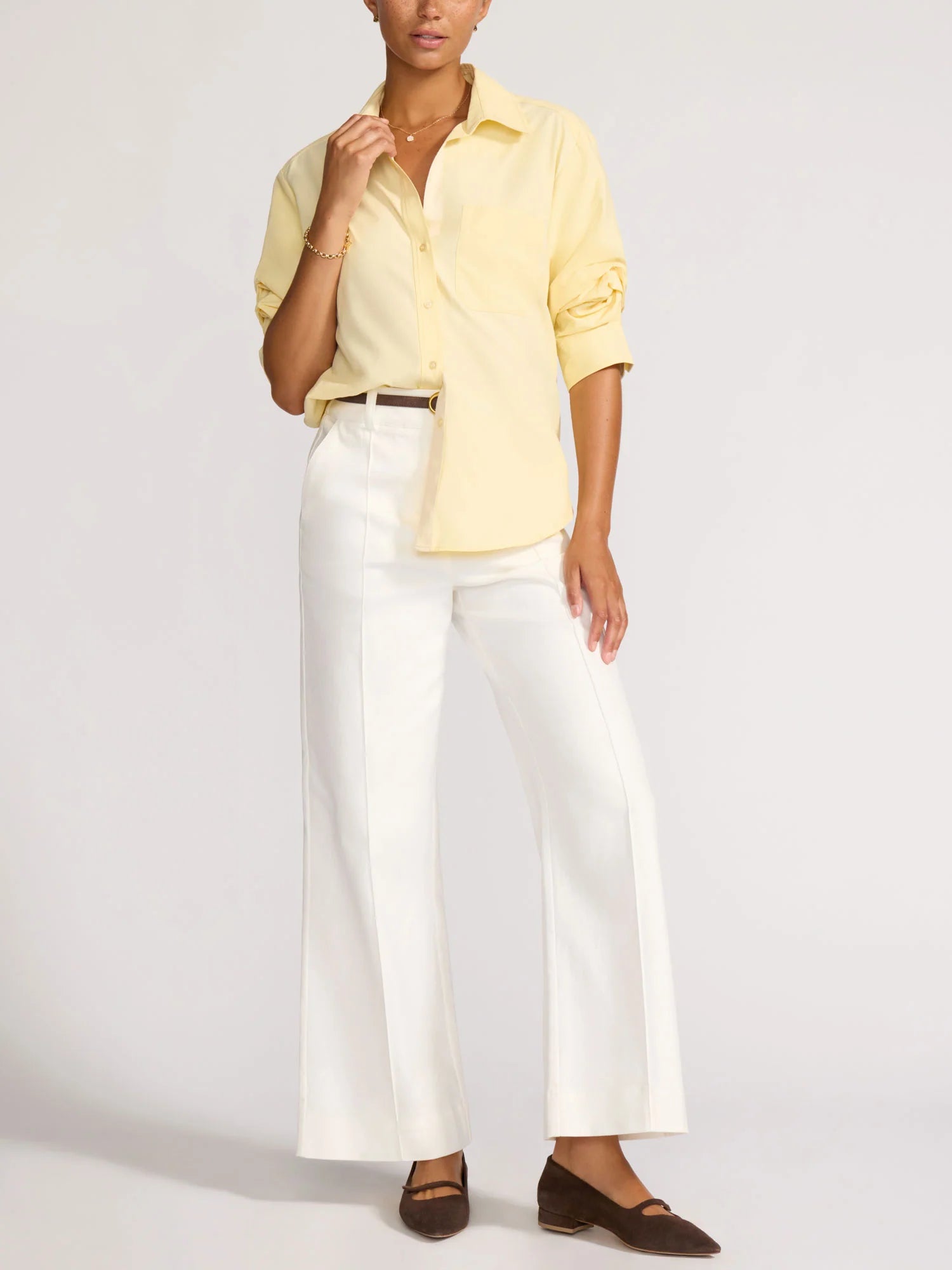 Person wearing a yellow shirt and white pants on a plain background
