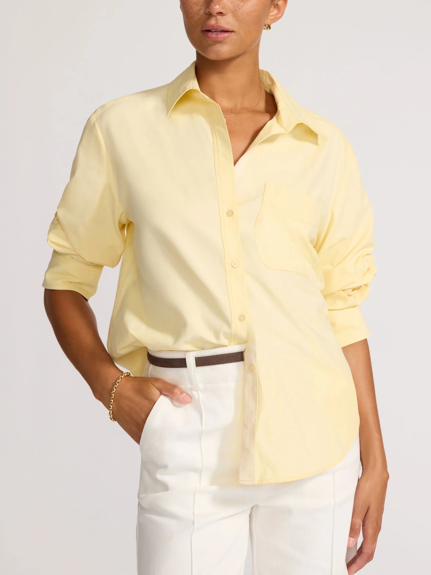Person wearing a light yellow shirt and white pants on a plain background