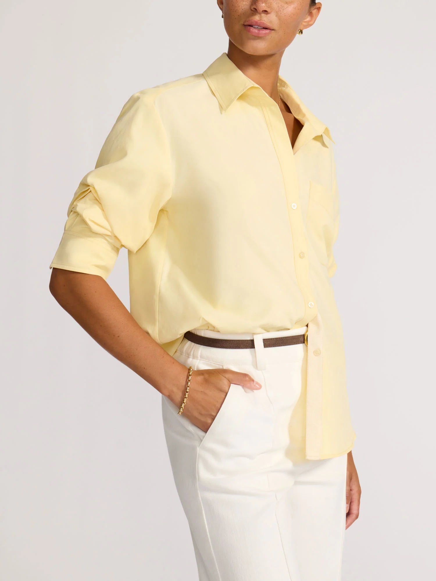 Person wearing a light yellow shirt and white pants on a plain background