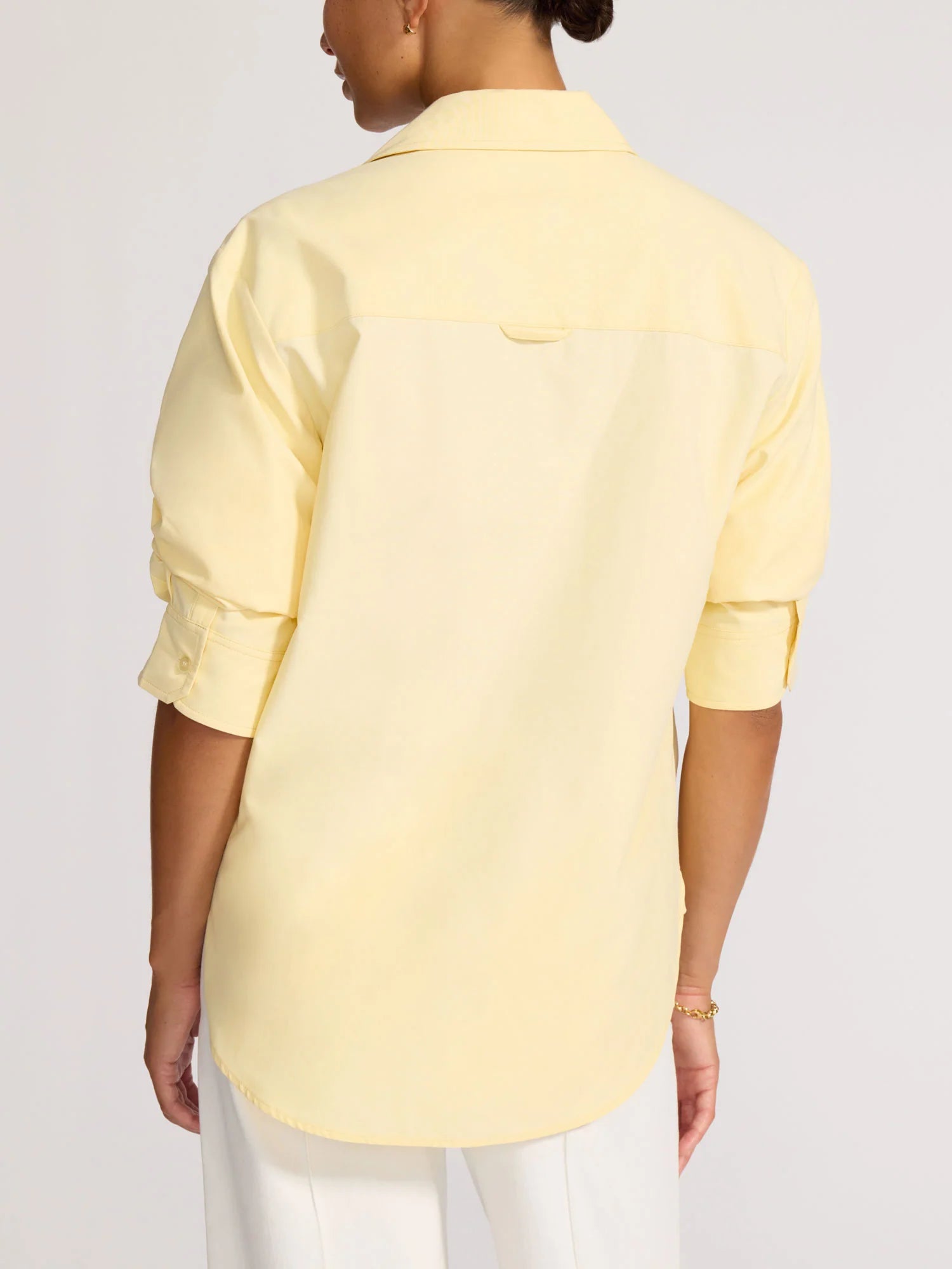 Person wearing a light yellow shirt on a white background