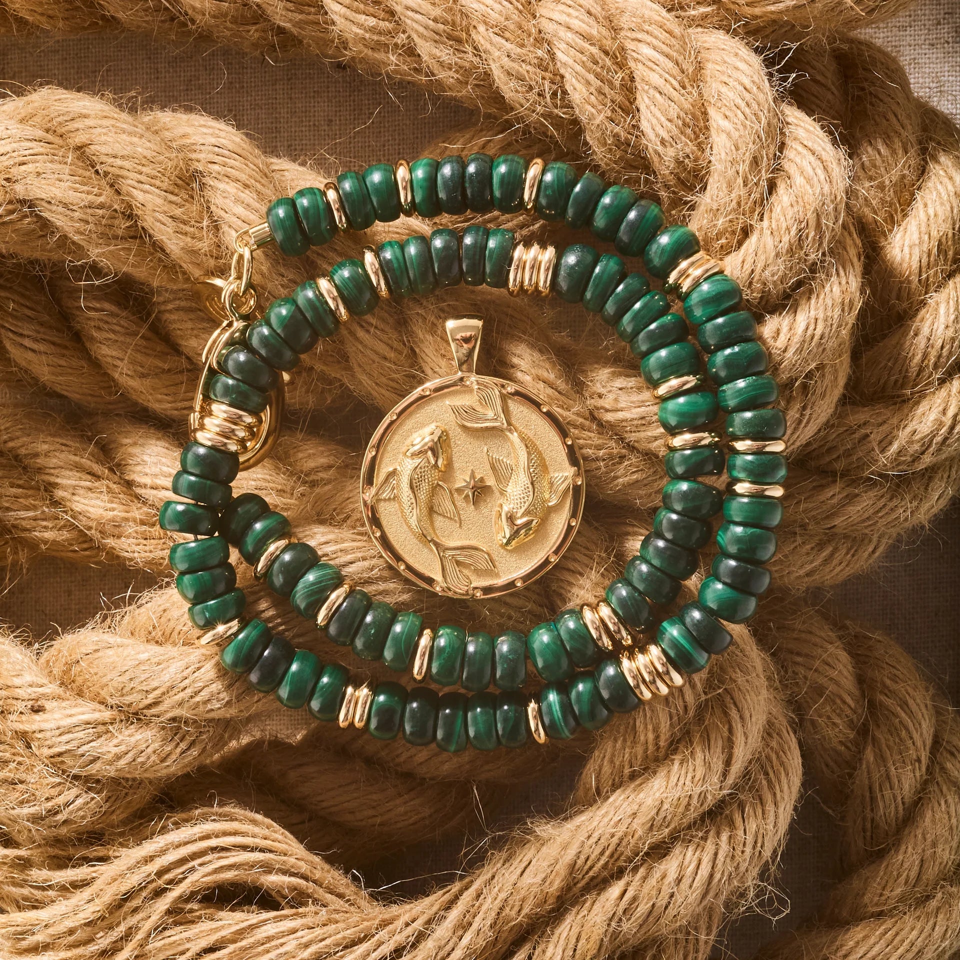 Green beaded bracelet with a gold pendant on a braided rope background