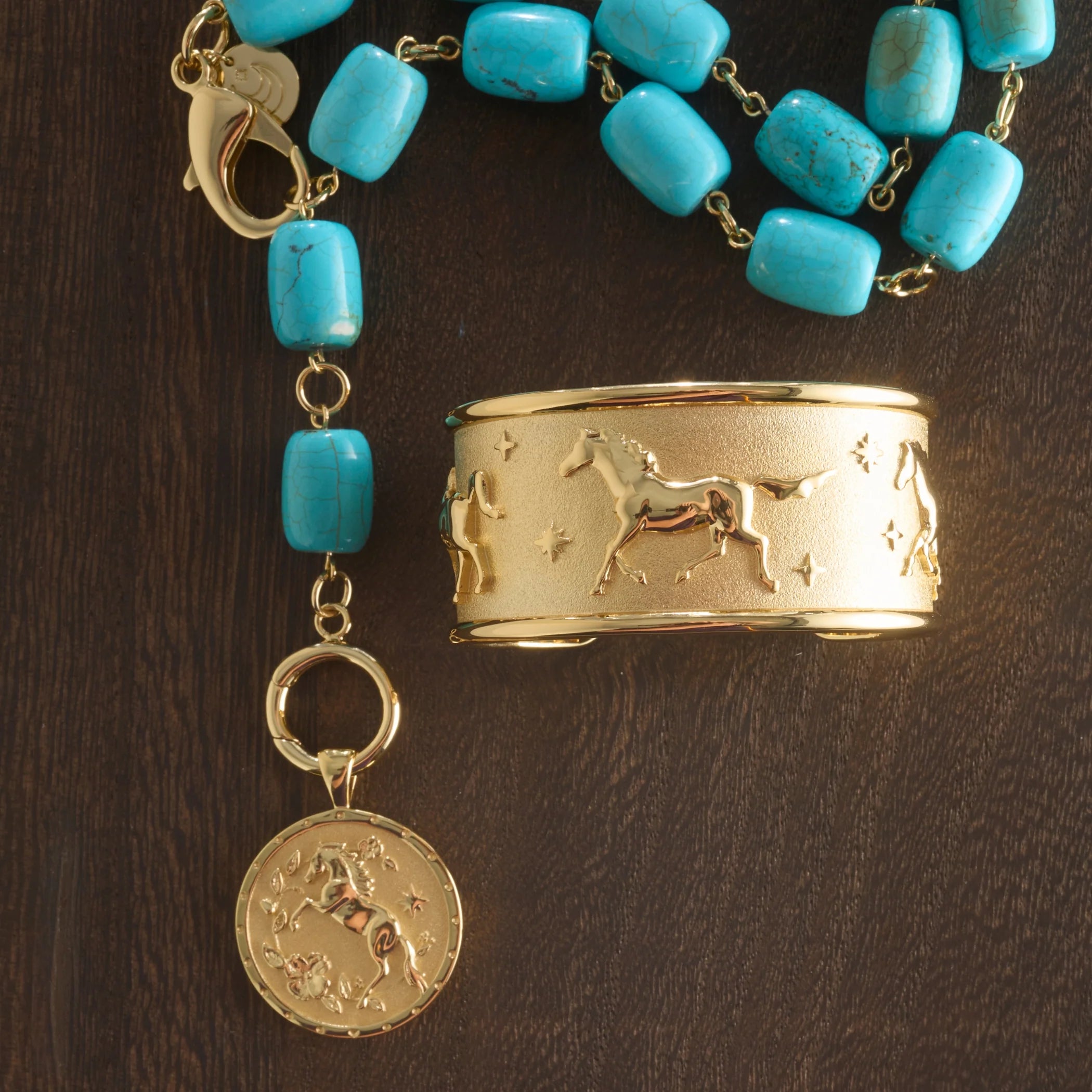 Gold bracelet with turquoise beads and a gold coin charm on a dark wooden surface
