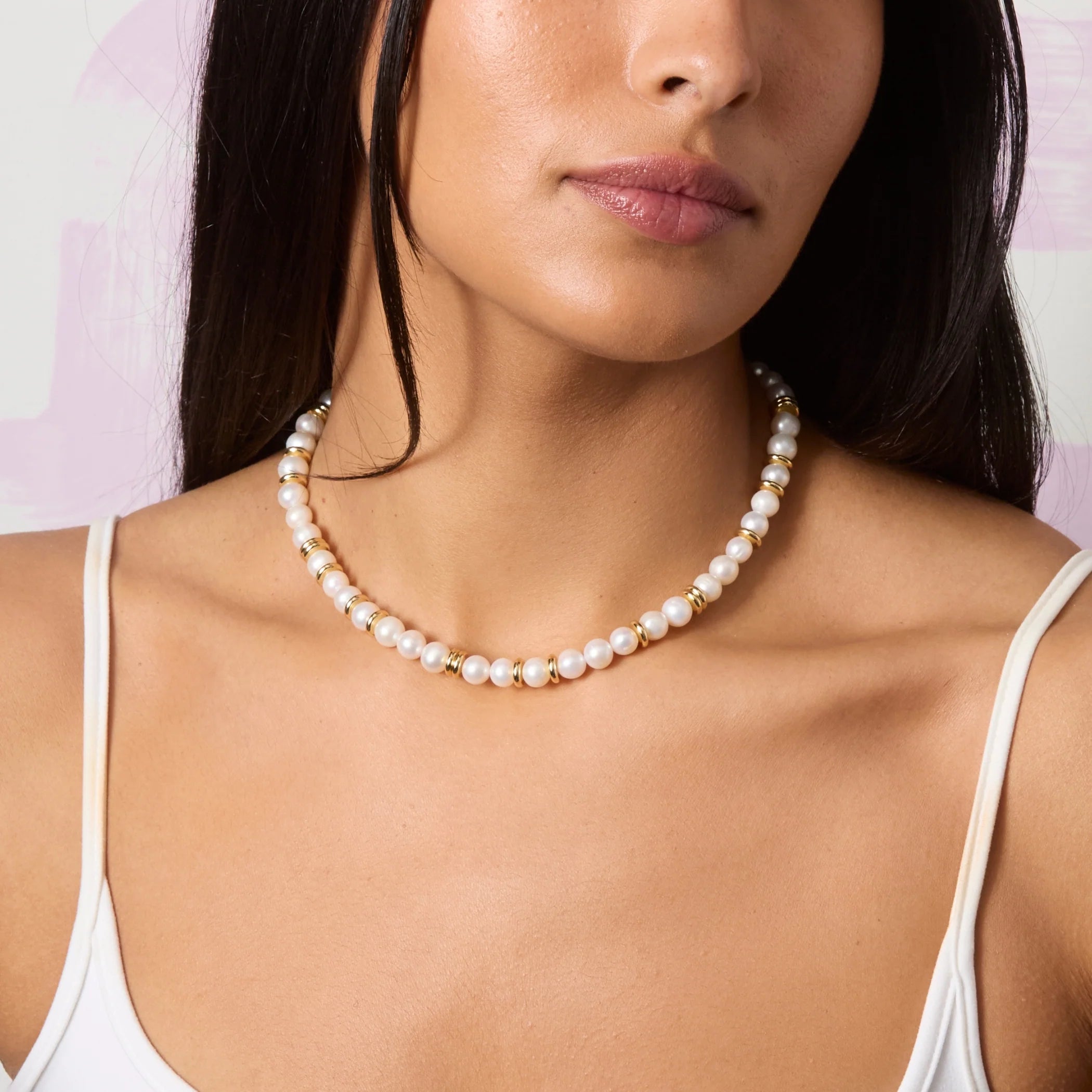 Woman wearing a pearl necklace against a light background