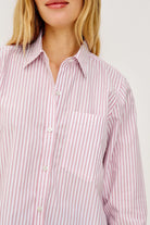Close-up of a person wearing a pink and white striped shirt on a plain background