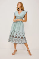 Woman wearing a light blue dress with lace details on a white background