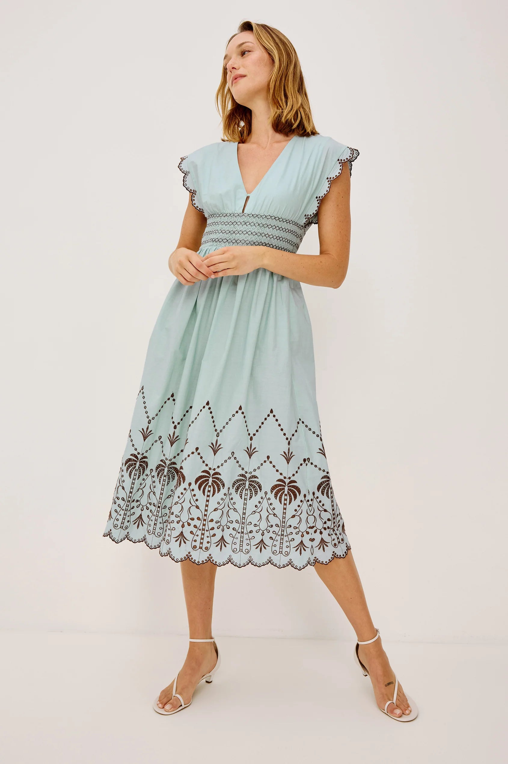 Woman wearing a light blue dress with lace details on a white background
