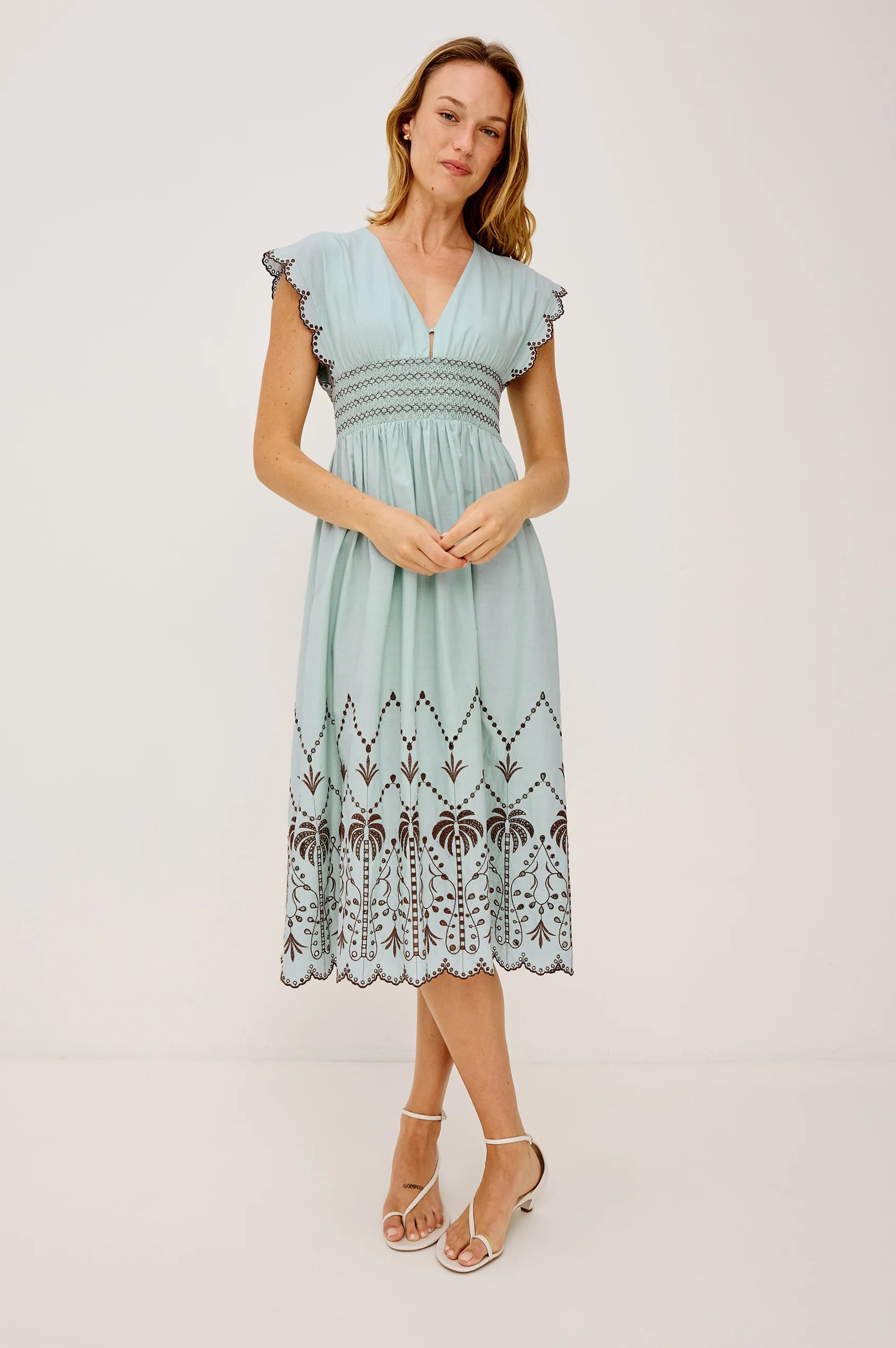 Woman wearing a light blue dress with lace details on a white background