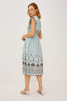 Woman wearing a light blue dress with lace details on a white background