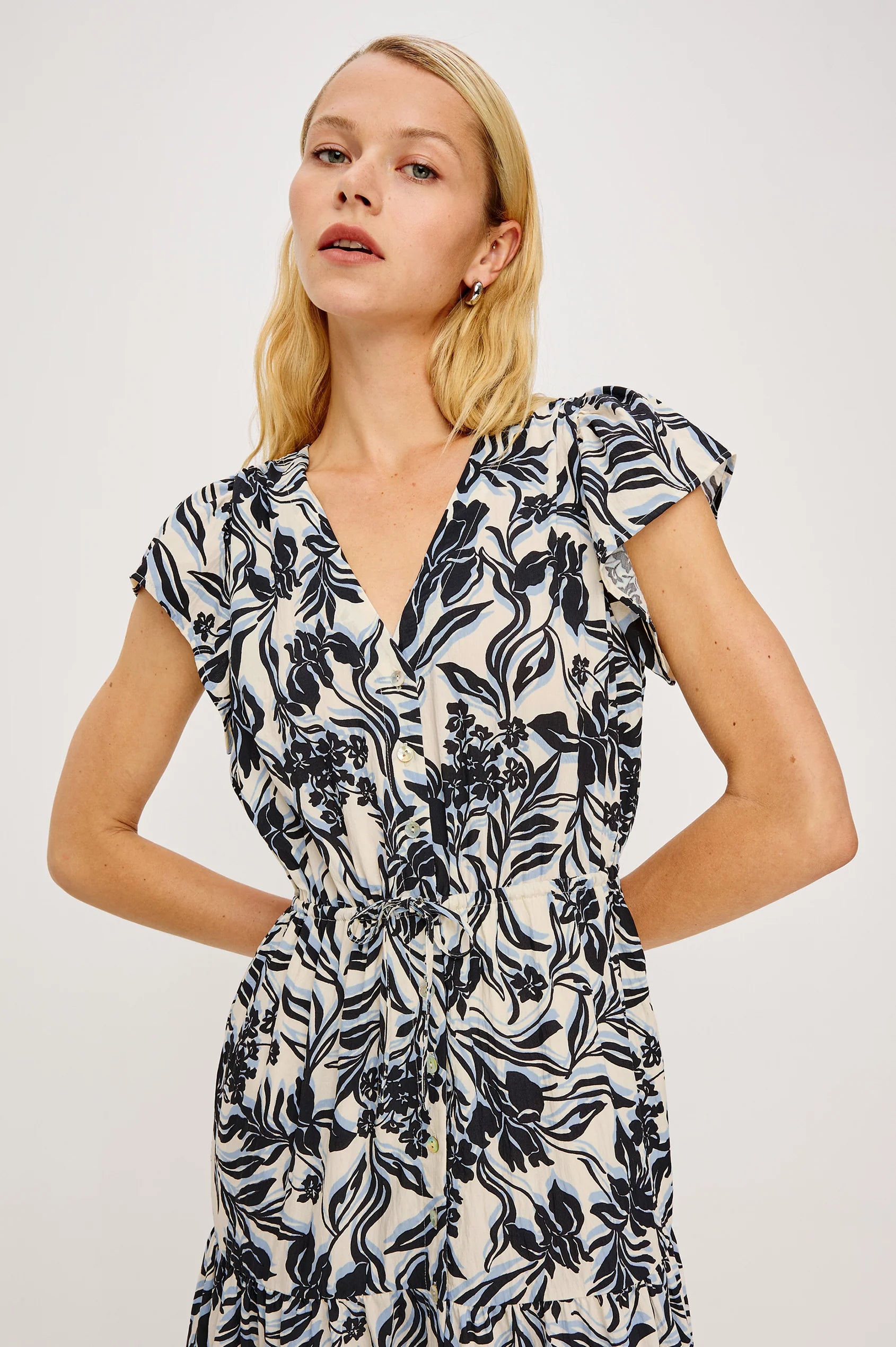 Woman wearing a black and white floral dress against a plain background
