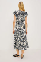 Woman wearing a black and white floral dress on a plain background