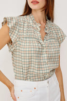 Woman wearing a plaid shirt with ruffled sleeves against a white background