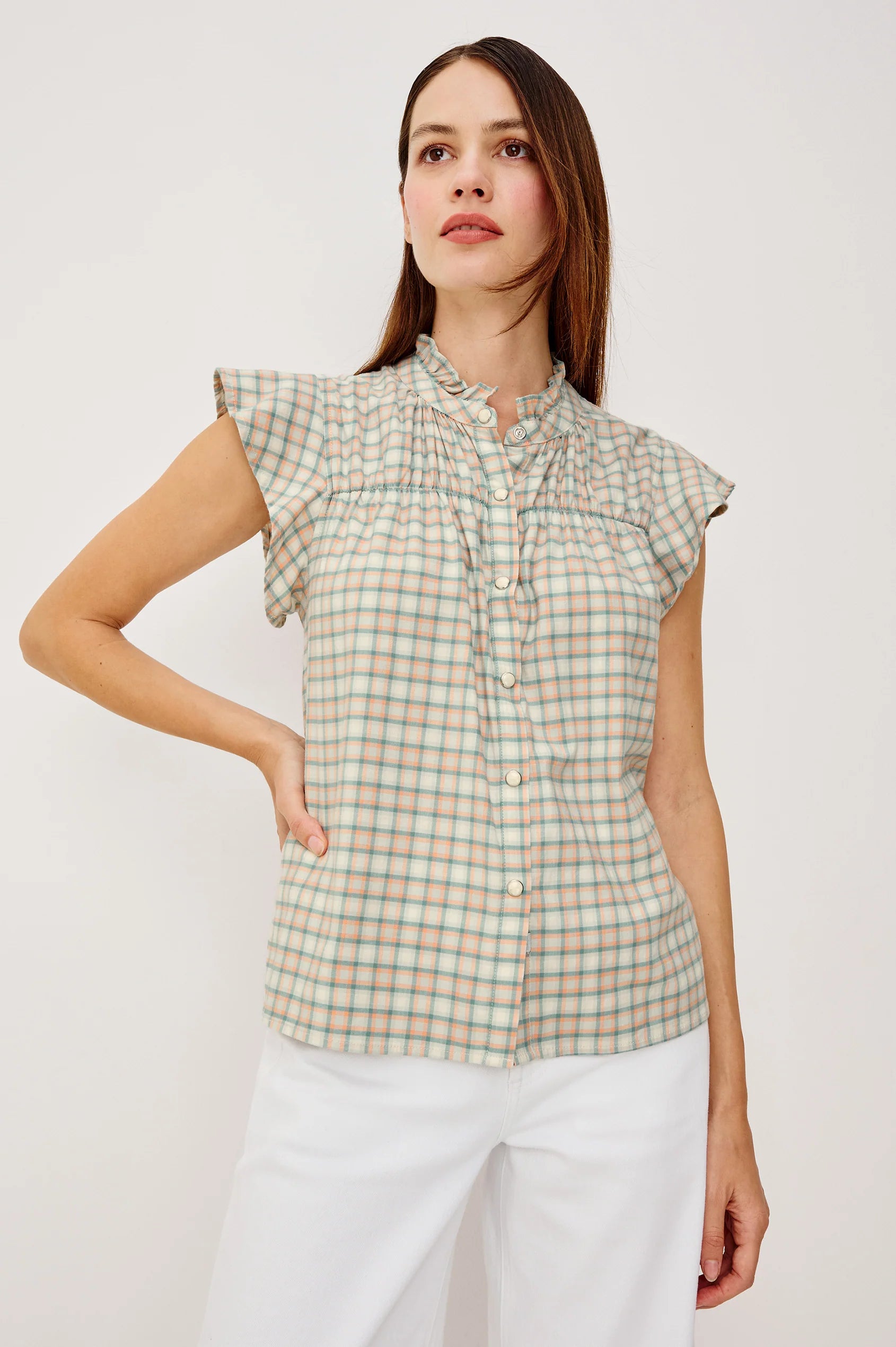 Woman wearing a plaid shirt and white pants on a plain background