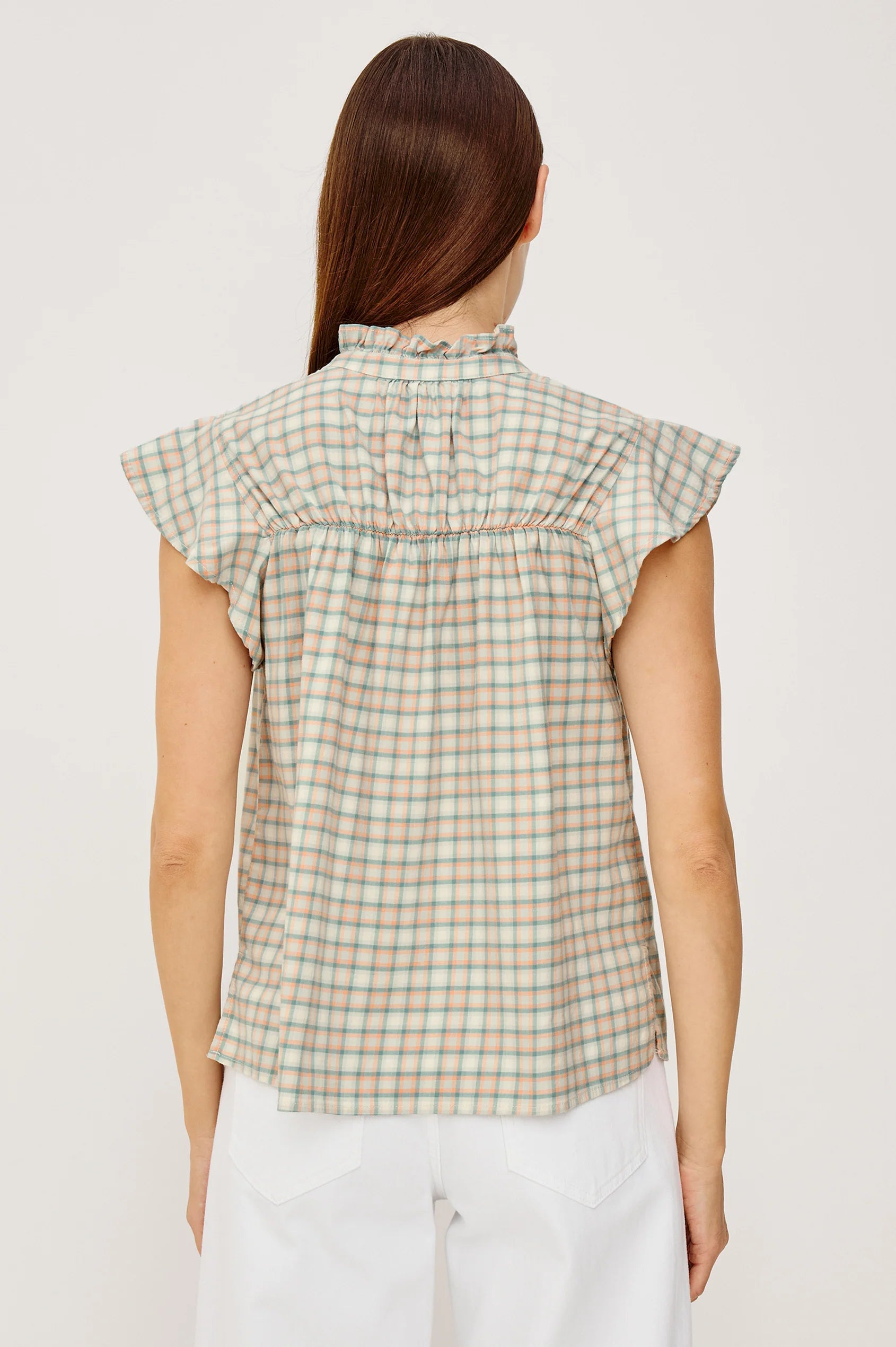 Woman wearing a plaid sleeveless top against a plain background