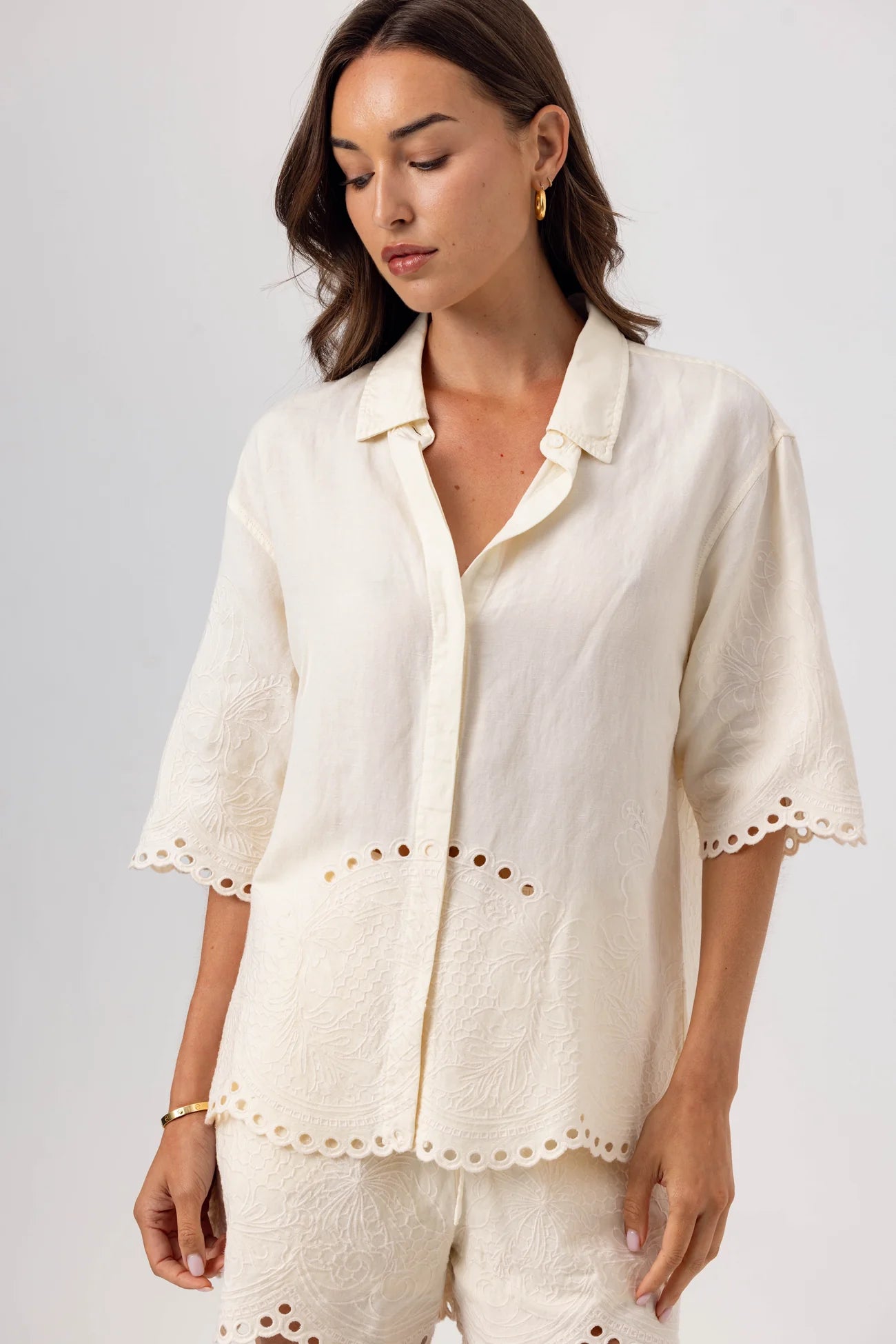 Woman wearing a white embroidered outfit against a plain background